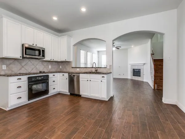 a kitchen with stainless steel appliances a white stove top oven cabinets and a wooden floor