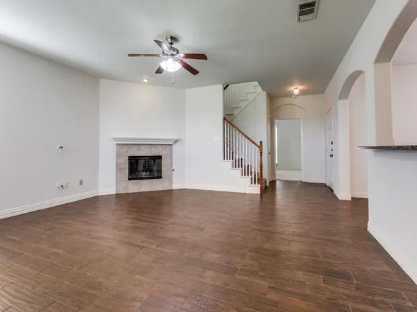 a view of an empty room with wooden floor and a ceiling fan