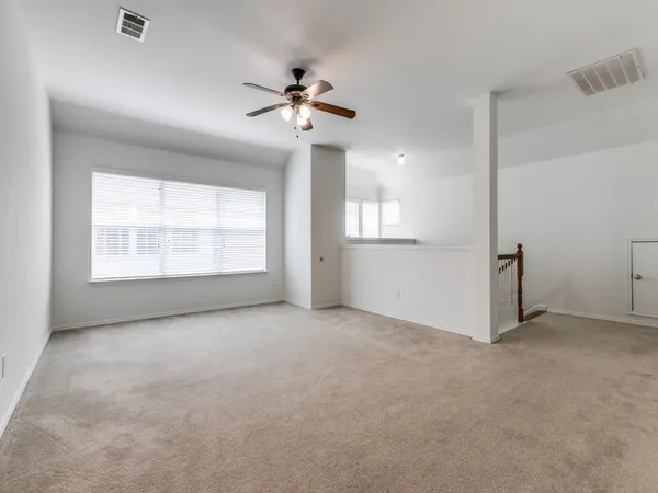 an empty room with windows and chandelier fan