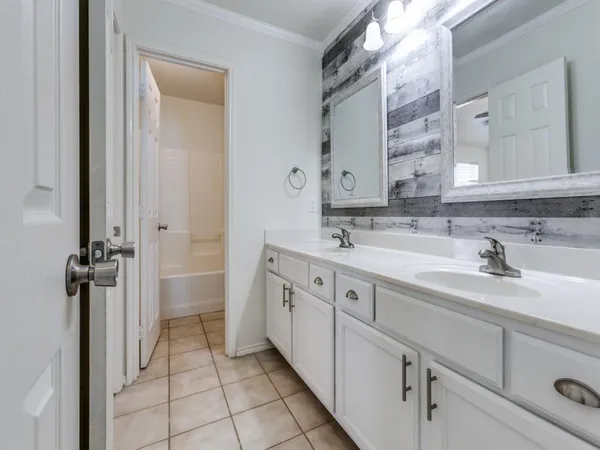 a spacious bathroom with a double vanity sink a mirror and a bathtub