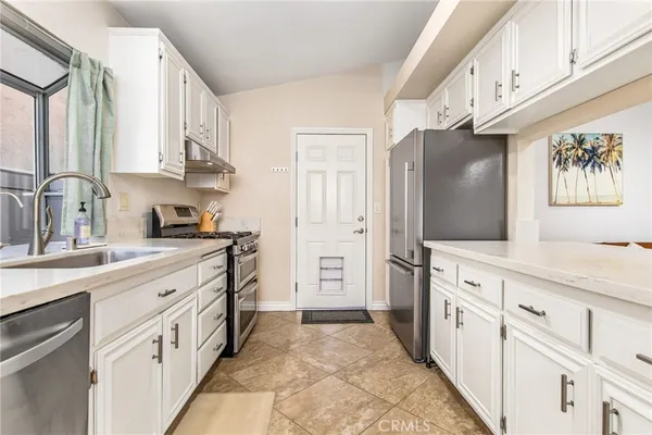a large kitchen with stainless steel appliances granite countertop a refrigerator and a sink