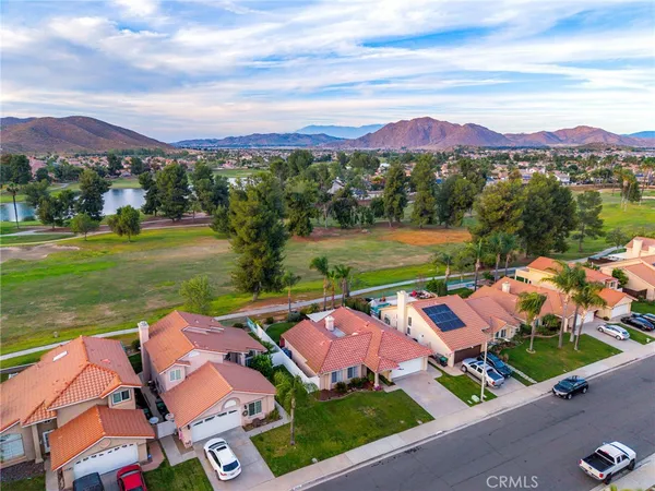 an aerial view of residential houses with outdoor space and mountain view in back