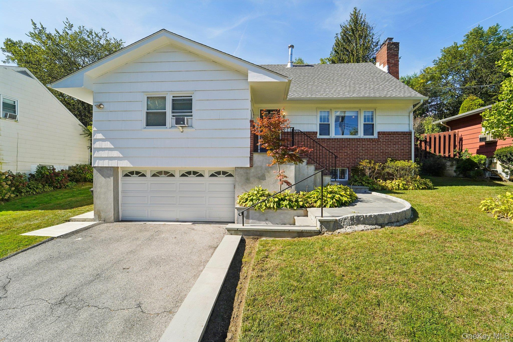Ranch-style home featuring a front yard, a chimney, driveway, and an attached garage