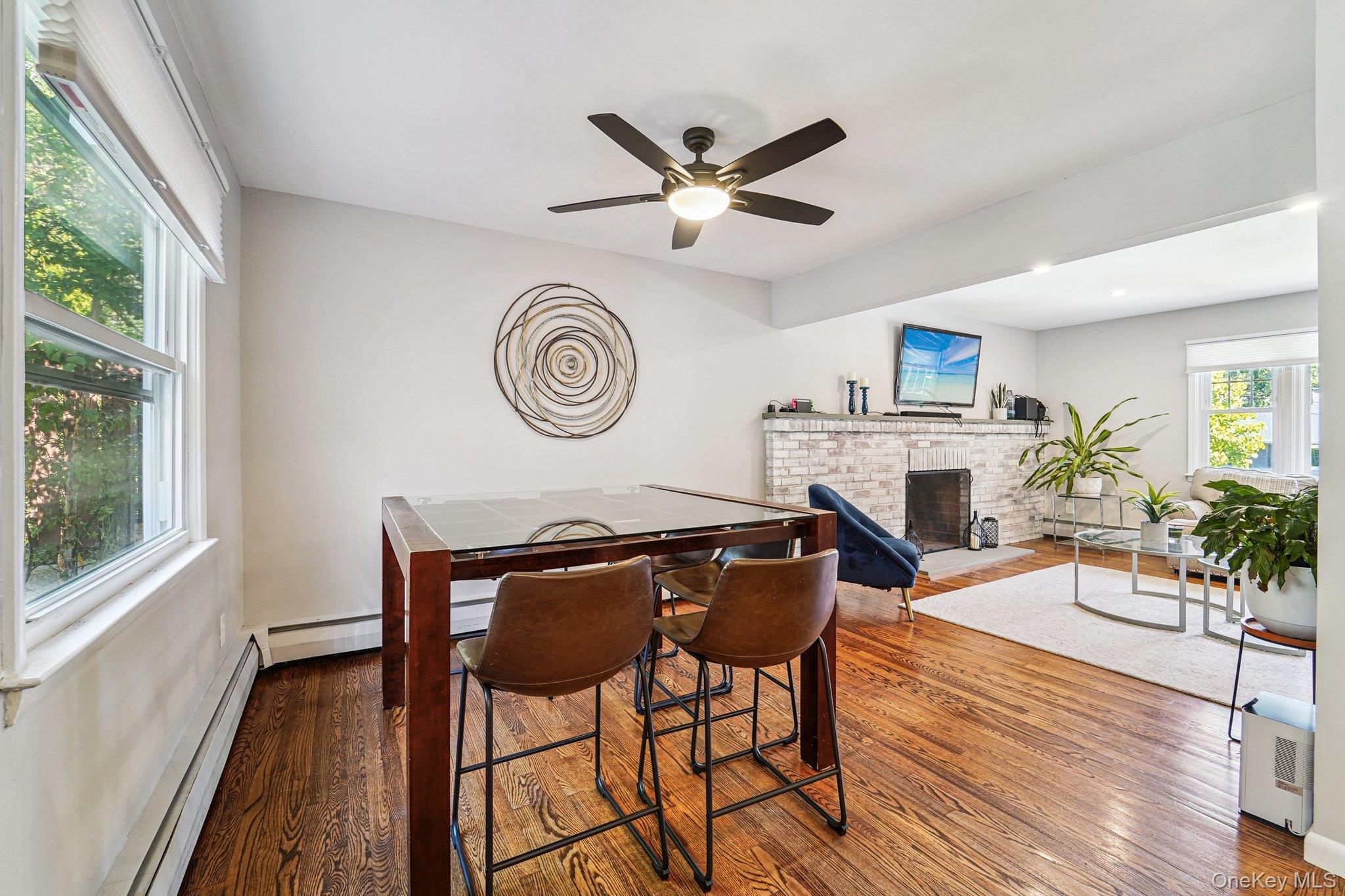 252 County Center Road White Plains, NY 10603 - Photo 11 of 44 Dining area with dark wood-style flooring, a brick fireplace, baseboard heating, and a ceiling fan