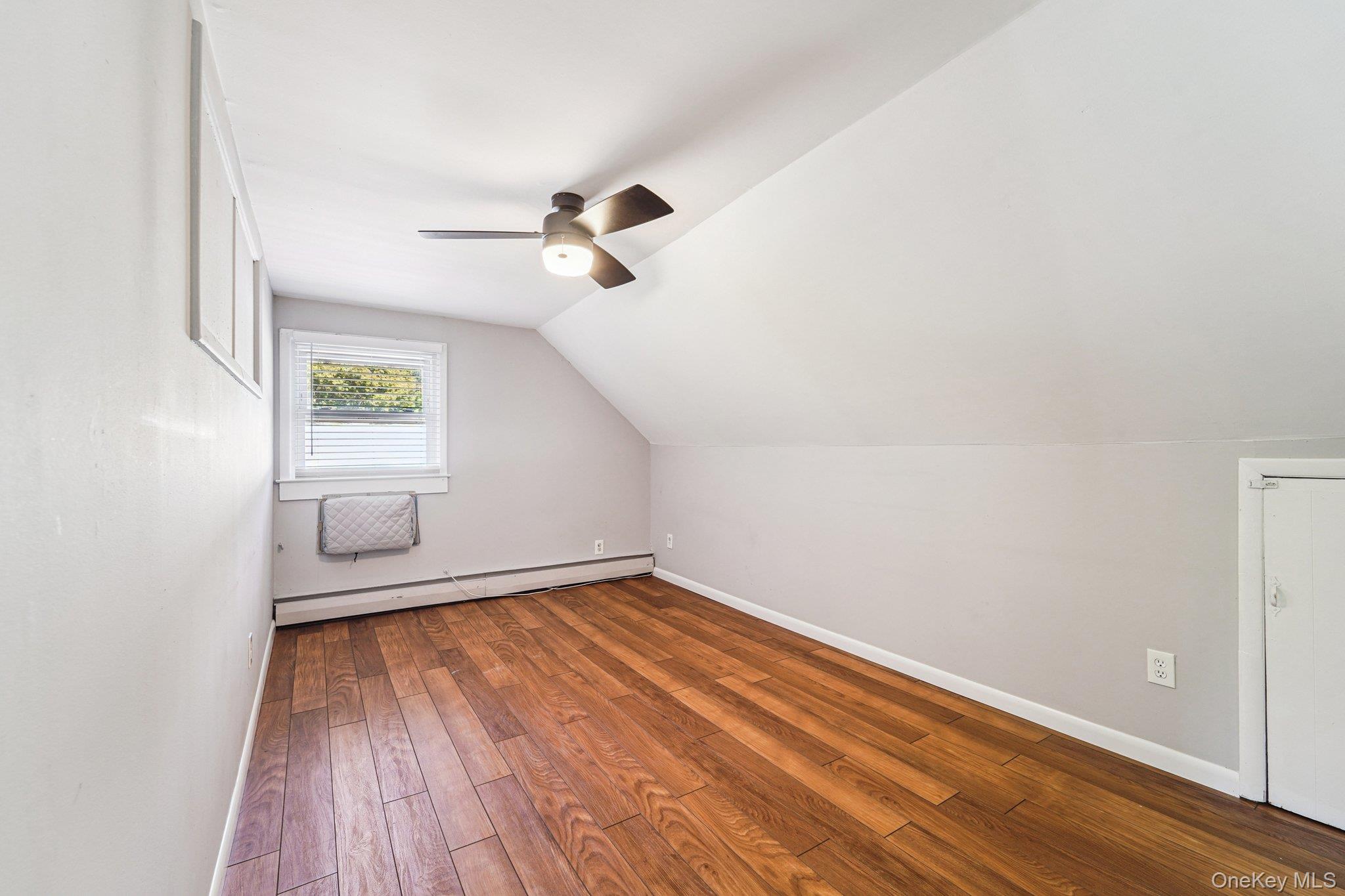 252 County Center Road White Plains, NY 10603 - Photo 21 of 44 Bonus room featuring wood-type flooring, a baseboard heating unit, lofted ceiling, a wall unit AC, and a ceiling fan