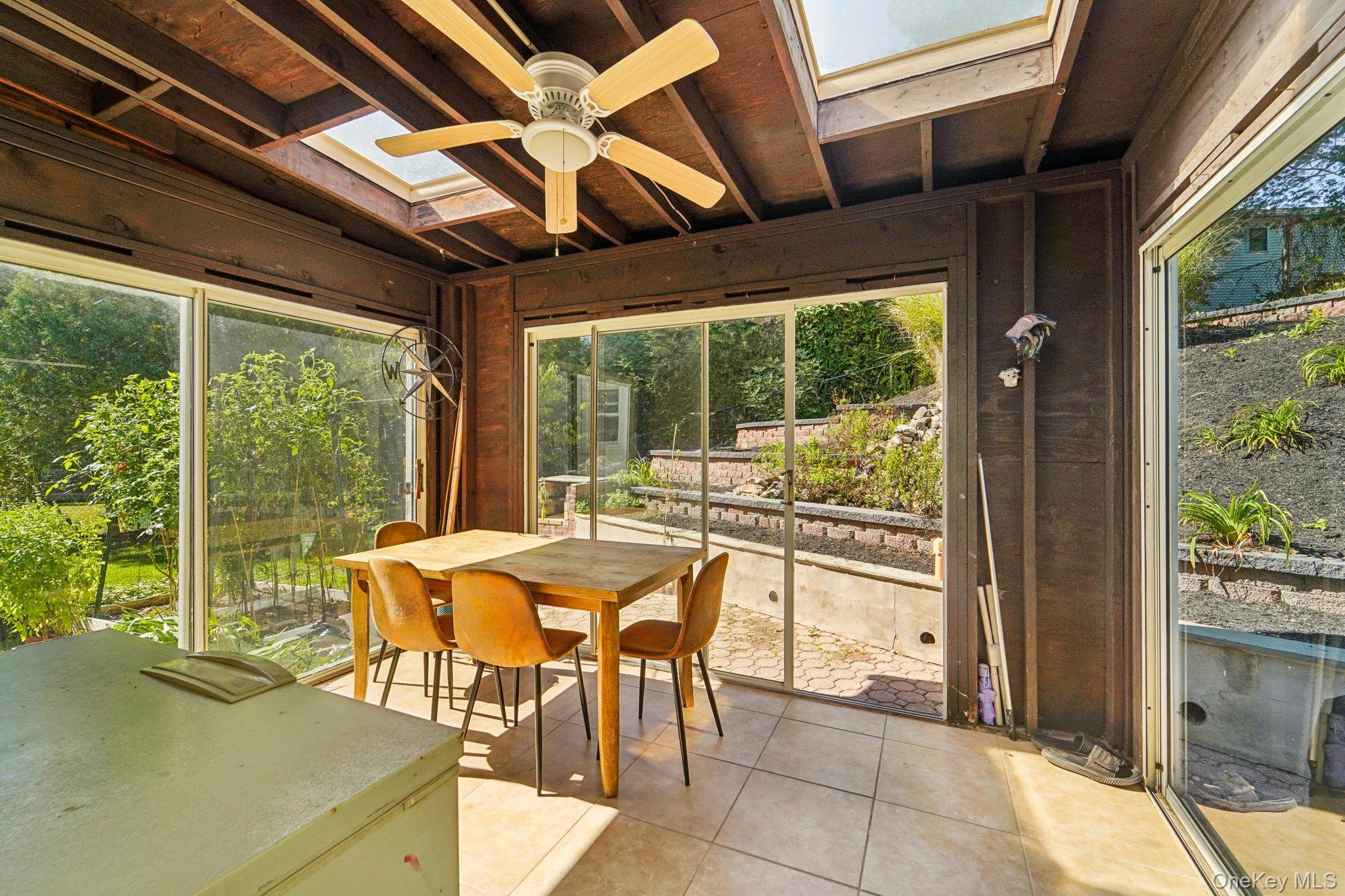 252 County Center Road White Plains, NY 10603 - Photo 33 of 44 Sunroom featuring a skylight, ceiling fan, tile patterned flooring, and outdoor dining area