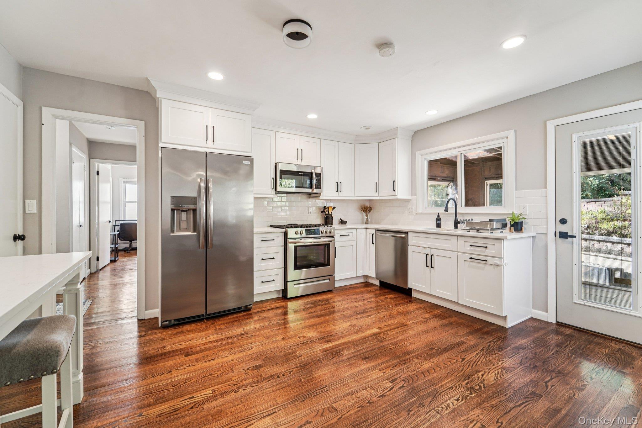 252 County Center Road White Plains, NY 10603 - Photo 6 of 44 Kitchen featuring stainless steel appliances, white cabinets, decorative backsplash, dark wood-style floors, and recessed lighting