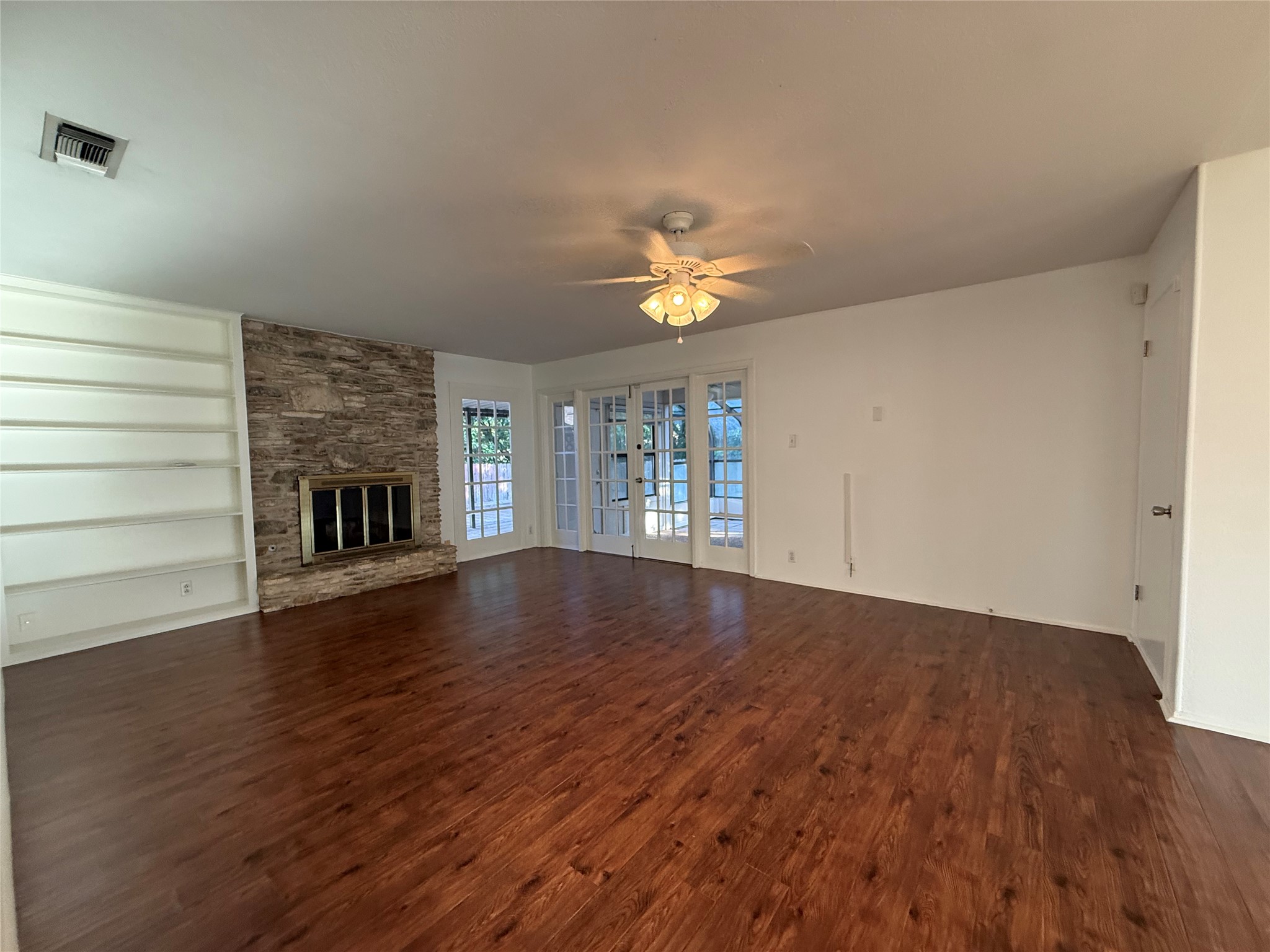 8713 Azalea Trail Austin, TX 78759 - Photo 6 of 13 A spacious living area showcasing rich hardwood floors and a striking stone fireplace.