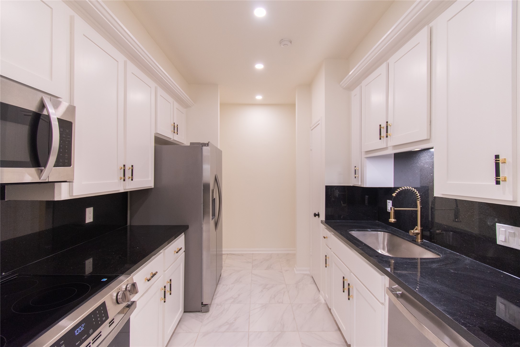727 Bunker Hill Road, Unit 43 Houston, TX 77024 - Photo 11 of 34 Stainless steel appliances, including a fridge and microwave, complement the contemporary design. The space is well-lit with recessed lighting and has a clean, polished look.