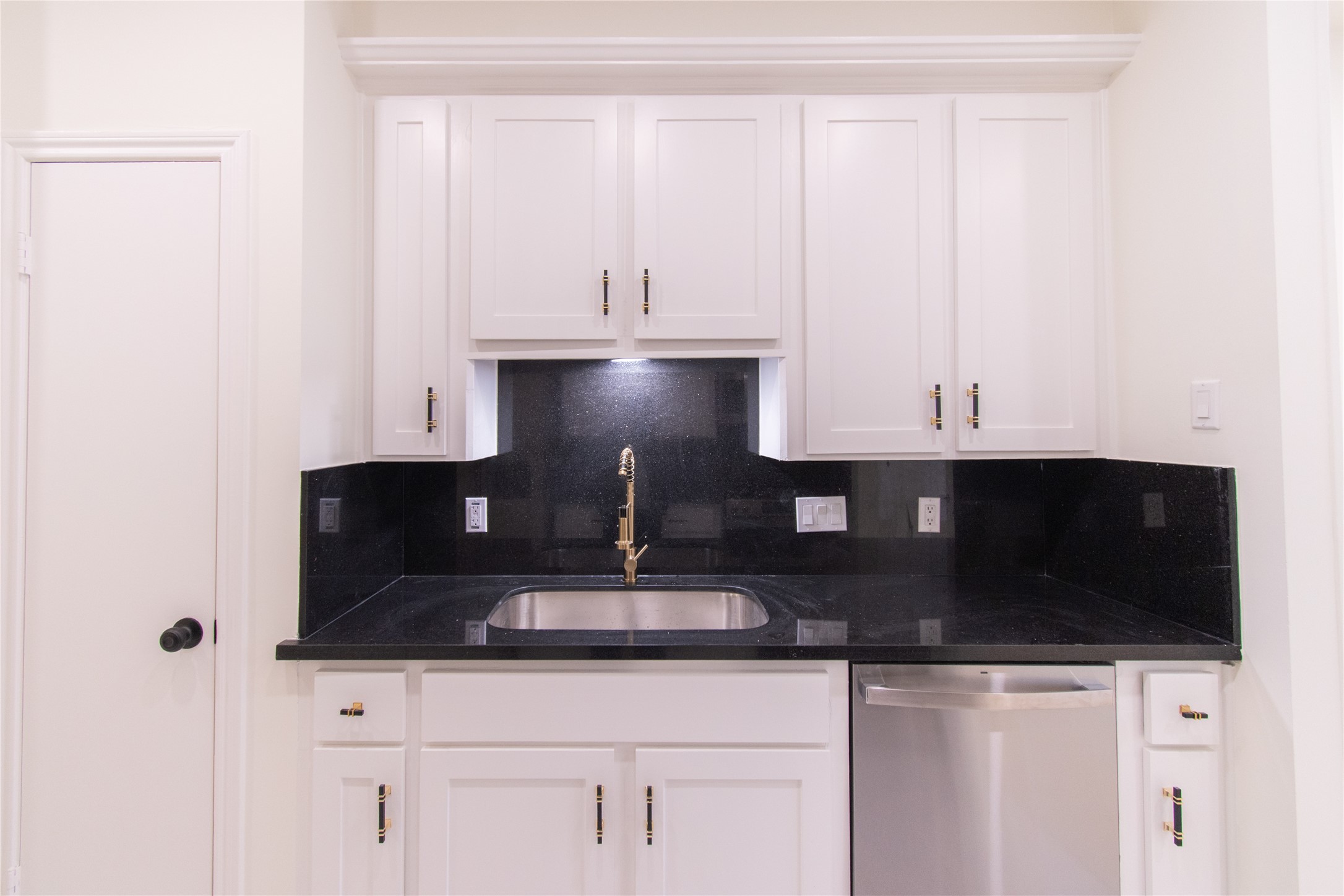 727 Bunker Hill Road, Unit 43 Houston, TX 77024 - Photo 12 of 34 This kitchen features sleek white cabinetry and black granite countertops, complete with a stainless steel sink and dishwasher, offering a modern and functional workspace.