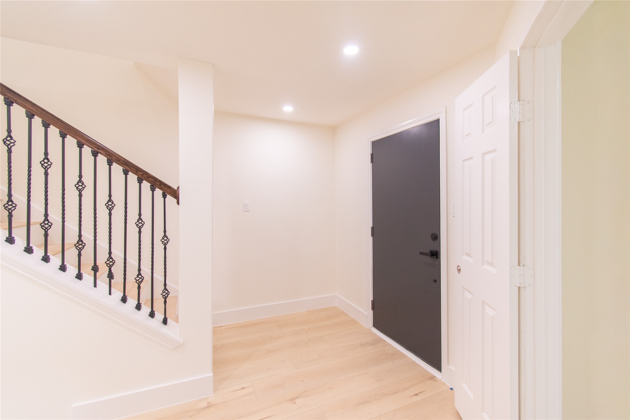 727 Bunker Hill Road, Unit 43 Houston, TX 77024 - Photo 17 of 34 Bright entryway with light wood flooring, a black front door, and a staircase with decorative iron railings. The walls are painted in a light color, creating a welcoming atmosphere.