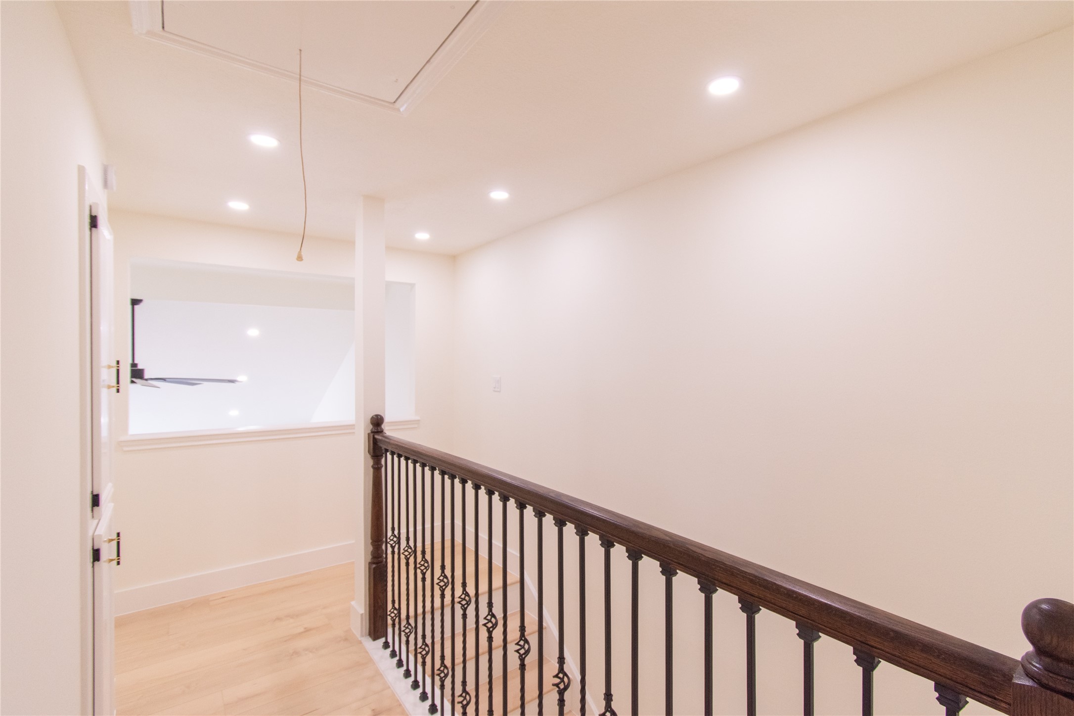 727 Bunker Hill Road, Unit 43 Houston, TX 77024 - Photo 18 of 34 Bright and airy upstairs hallway with recessed lighting, featuring a wooden railing and iron balusters, overlooking an open space below.