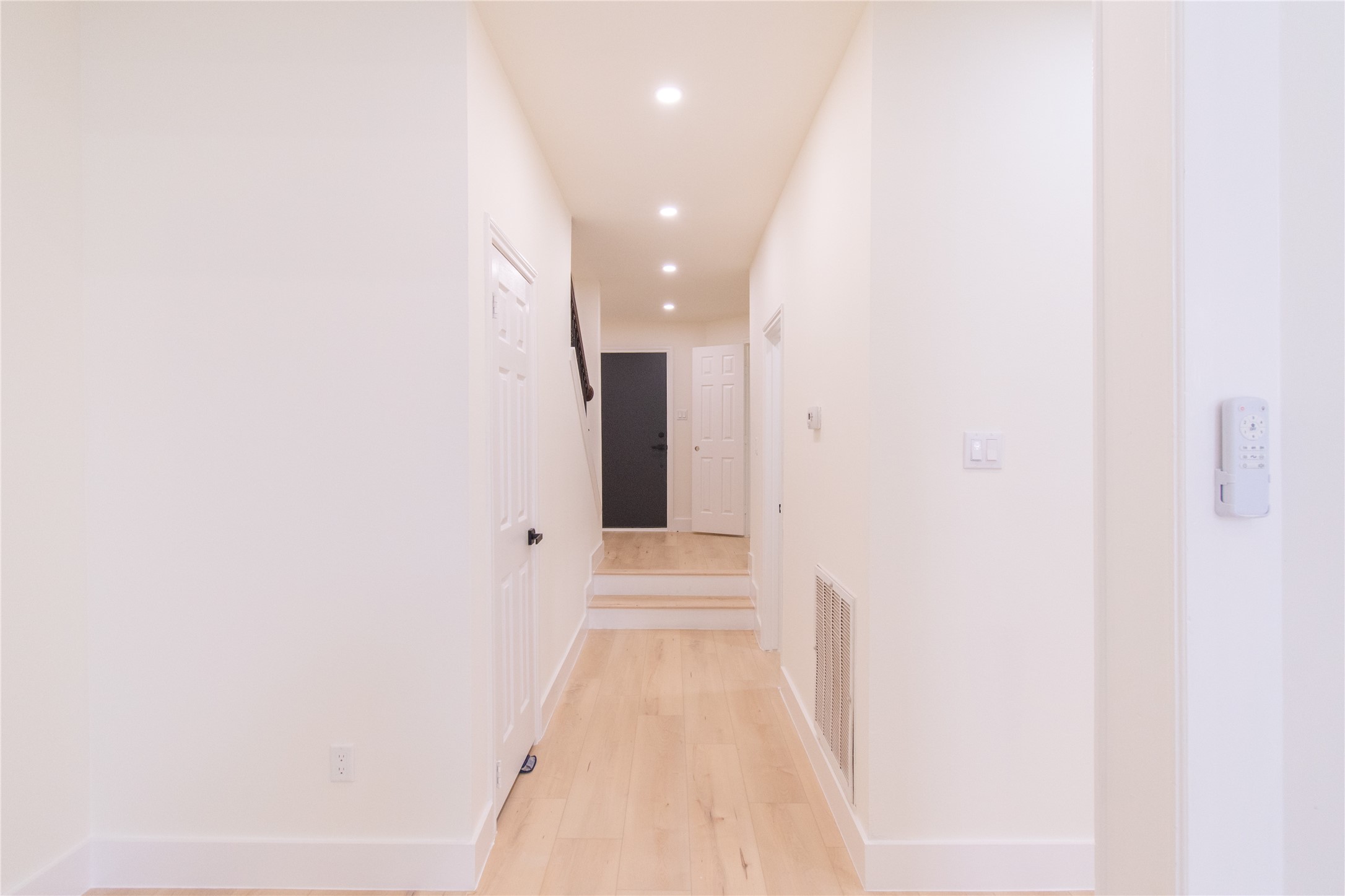 727 Bunker Hill Road, Unit 43 Houston, TX 77024 - Photo 20 of 34 Bright, welcoming hallway with light wood flooring, white walls, and recessed lighting. Multiple doors lead off the corridor, creating a spacious feel.