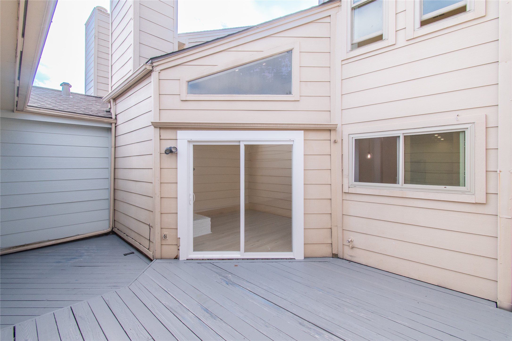 727 Bunker Hill Road, Unit 43 Houston, TX 77024 - Photo 31 of 34 Spacious outdoor patio with light-colored siding, featuring a sliding glass door and two windows, ideal for indoor-outdoor living.