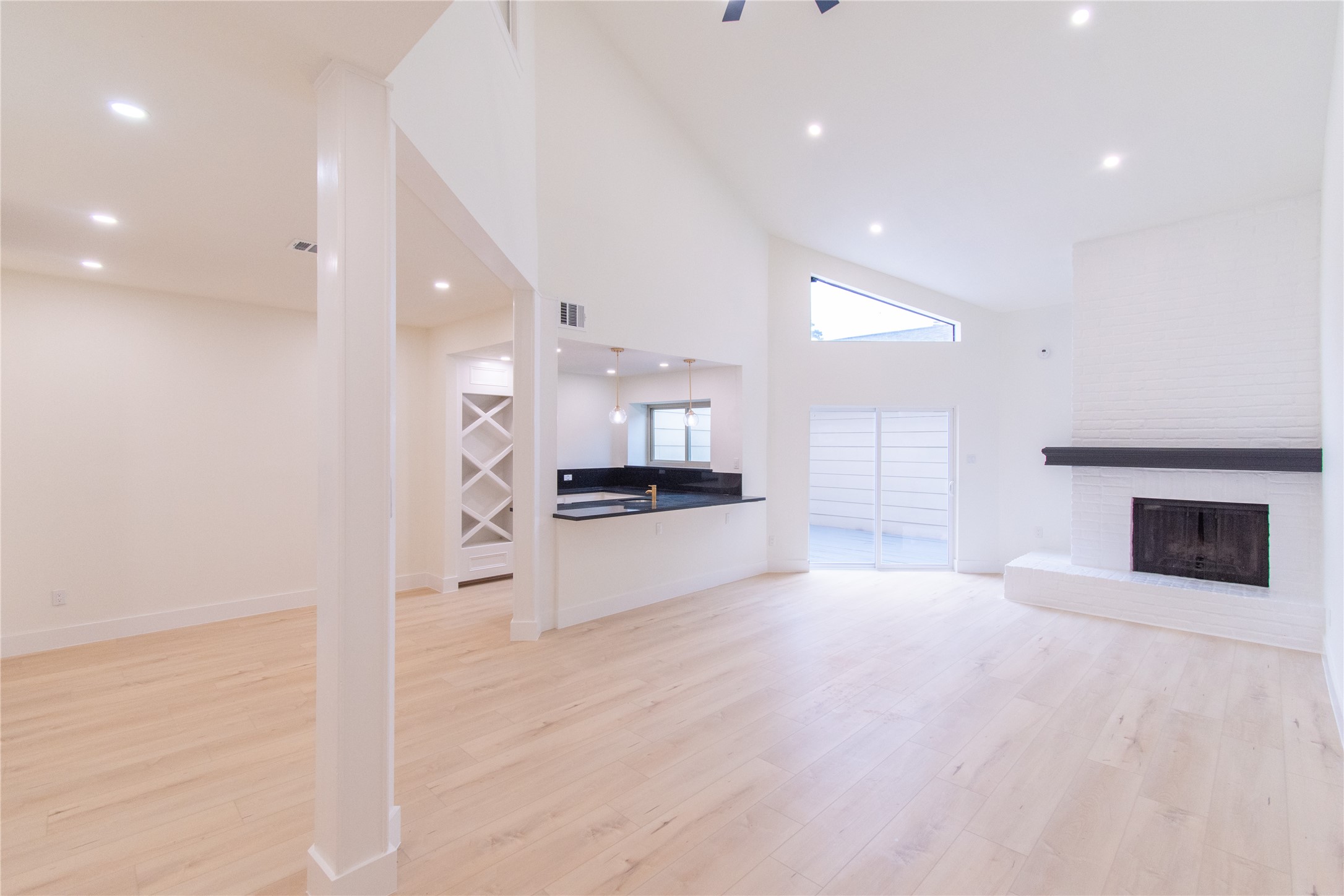 727 Bunker Hill Road, Unit 43 Houston, TX 77024 - Photo 34 of 34 High ceilings, a modern open floor plan, a sleek kitchen with a pass-through, light wood floors, and a cozy white brick fireplace. Ideal for contemporary living.