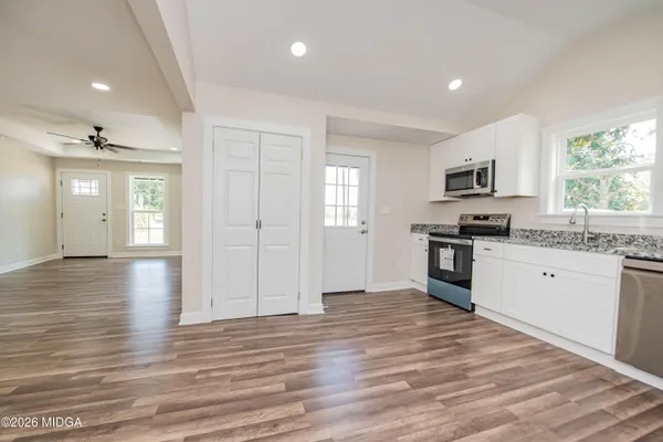 a large kitchen with granite countertop a stove and a wooden floor