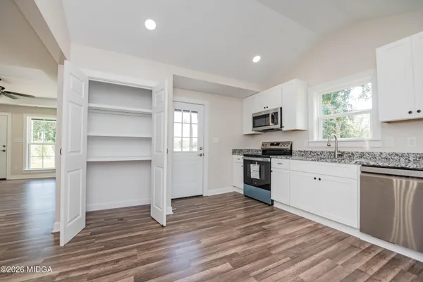 a kitchen with granite countertop a refrigerator stove top oven and sink