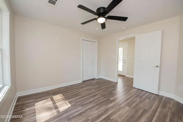 an empty room with wooden floor and a ceiling fan
