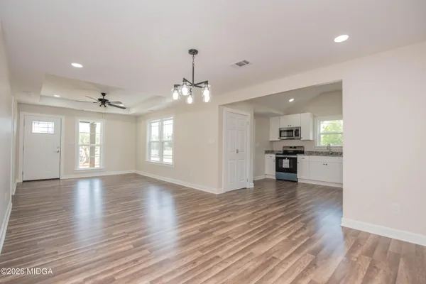 an empty room with wooden floor and kitchen view