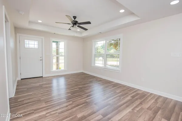 a view of an empty room with wooden floor and a window