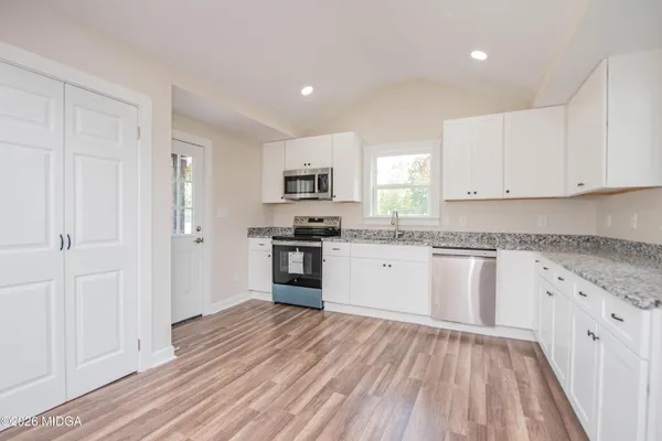 a kitchen with granite countertop white cabinets and stainless steel appliances