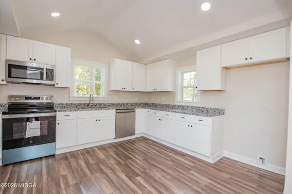 a kitchen with granite countertop a sink cabinets and stainless steel appliances