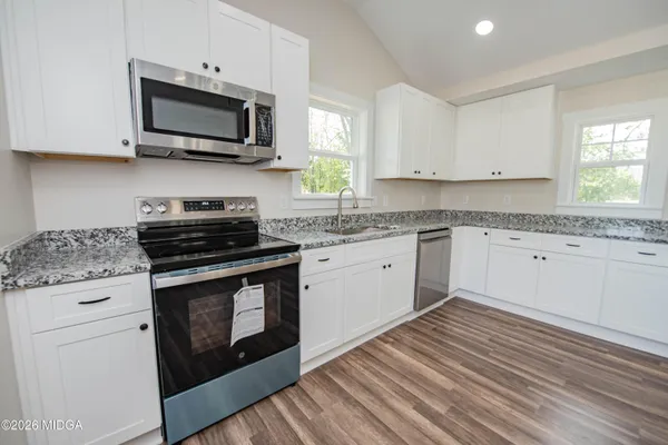 a kitchen with stainless steel appliances granite countertop a stove a sink and a microwave