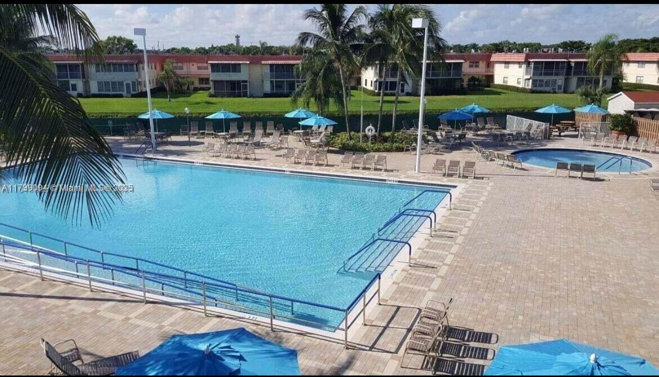 92 Saxony B, Unit B Delray Beach, FL 33446 - Photo 8 of 9 a view of a swimming pool with a patio and plants