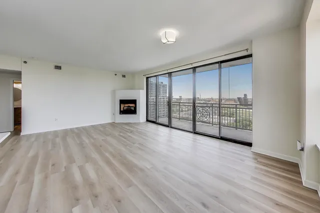 a view of an empty room with wooden floor and a window