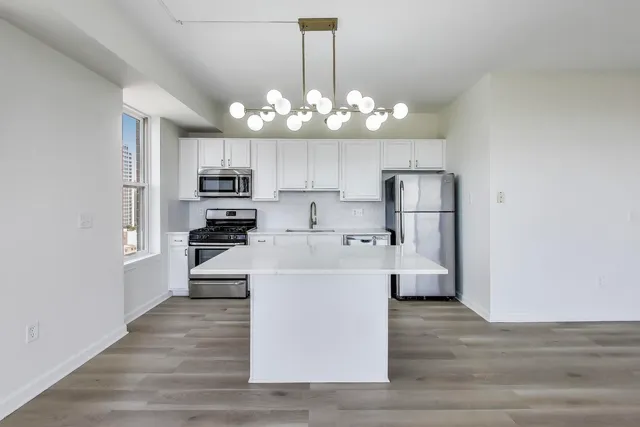 a large kitchen with white cabinets stainless steel appliances and chandelier