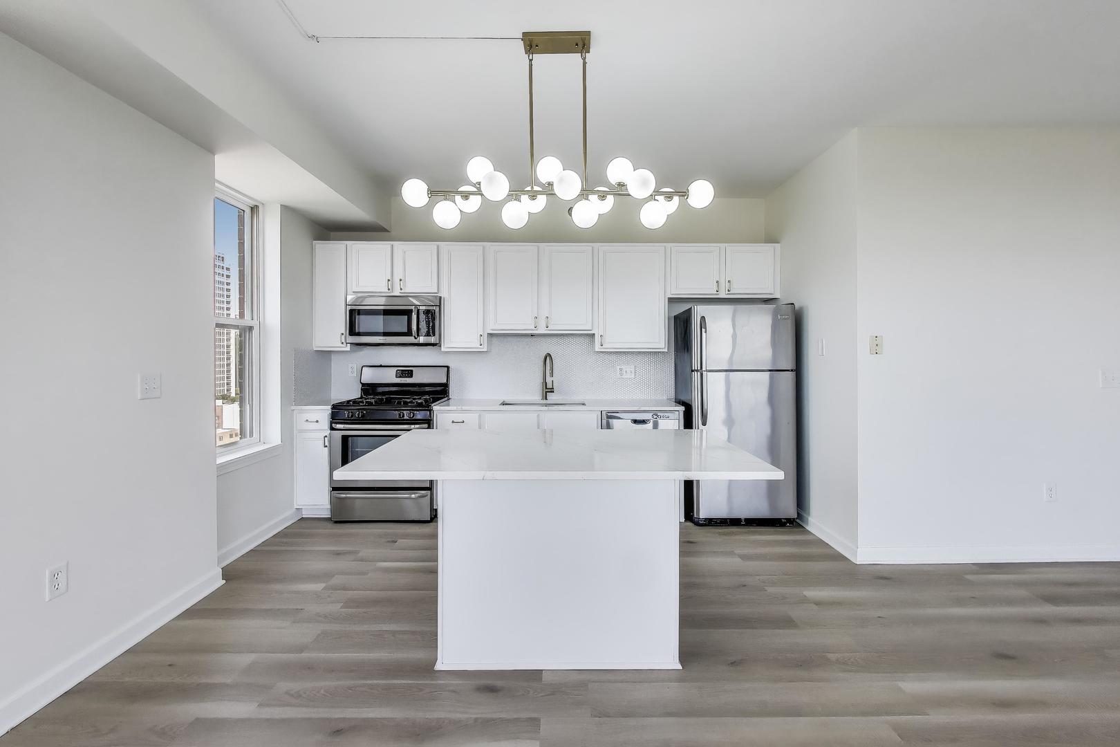 5 East 14th Place, Unit 1405 Chicago, IL 60605 - Photo 9 of 33 a large kitchen with white cabinets stainless steel appliances and chandelier
