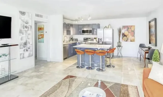 a room with stainless steel appliances kitchen island granite countertop furniture and a flat screen tv