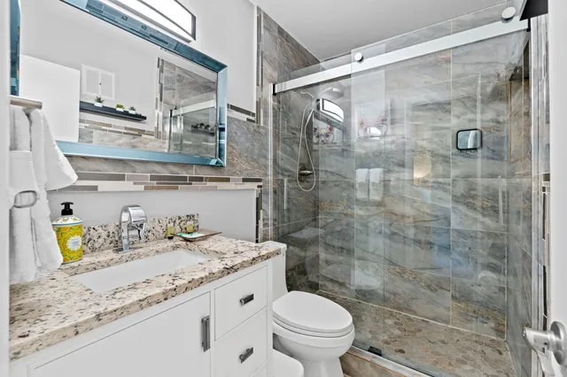 a bathroom with a granite countertop sink a toilet and shower