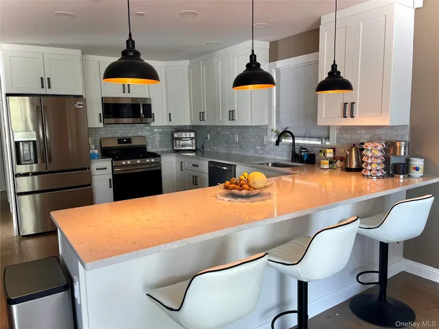 a kitchen with stainless steel appliances granite countertop a sink a stove a refrigerator and cabinets