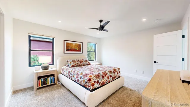 a bedroom with a bed next to a window with a bookshelf