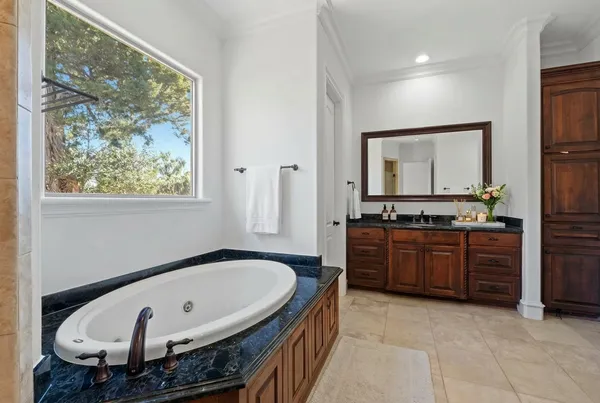 a spacious bathroom with a tub sink and mirror
