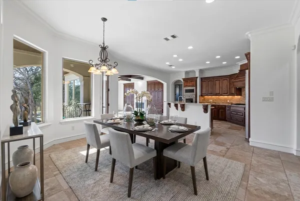 a dining room with furniture a chandelier and kitchen view