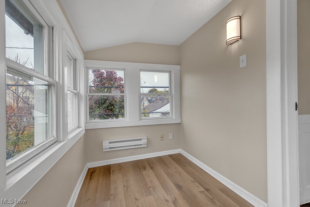 2127 Rossmoor Road Cleveland Heights, OH 44118 - Photo 12 of 21 Unfurnished room featuring baseboards, vaulted ceiling, a wall unit AC, and wood finished floors