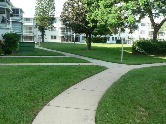 a view of a white house with a big yard and large trees