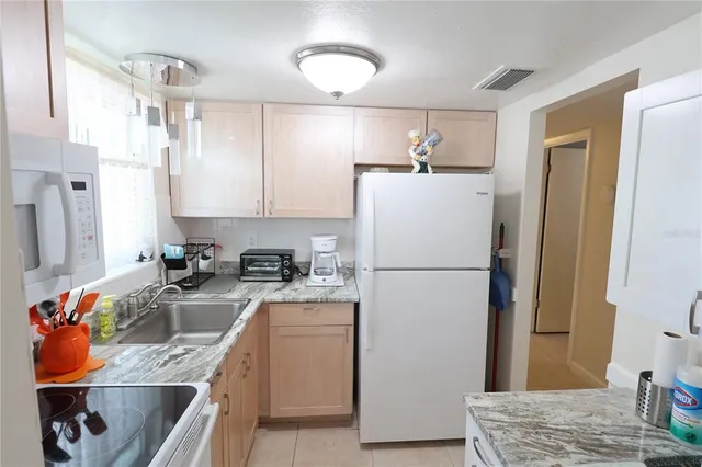 a kitchen with stainless steel appliances granite countertop a refrigerator a sink a stove a dining table and chairs