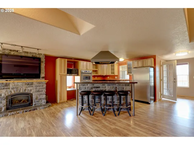 a kitchen with stainless steel appliances granite countertop a stove a refrigerator a sink a dining table and chairs with wooden floor