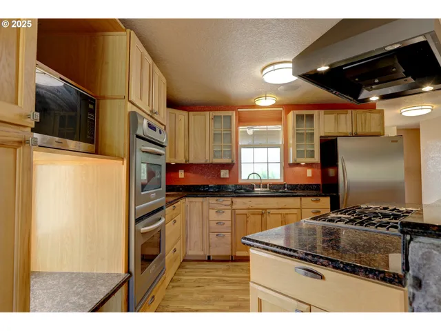 a kitchen with stainless steel appliances granite countertop a refrigerator and a stove top oven