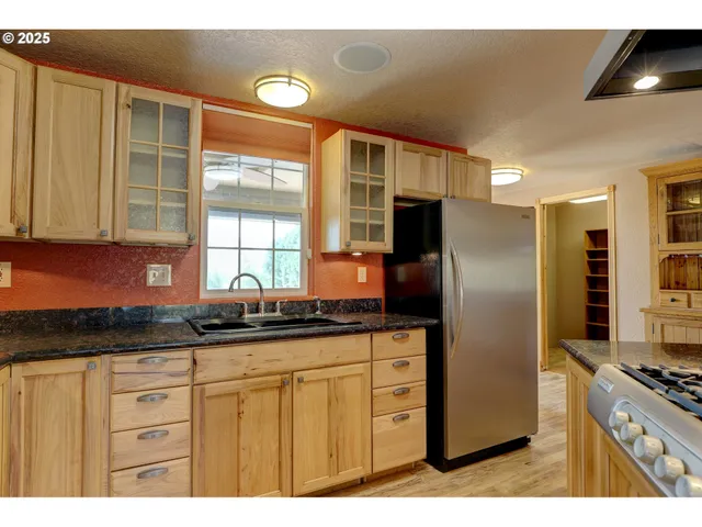 a kitchen with granite countertop a refrigerator a sink a stove a counter space and cabinets