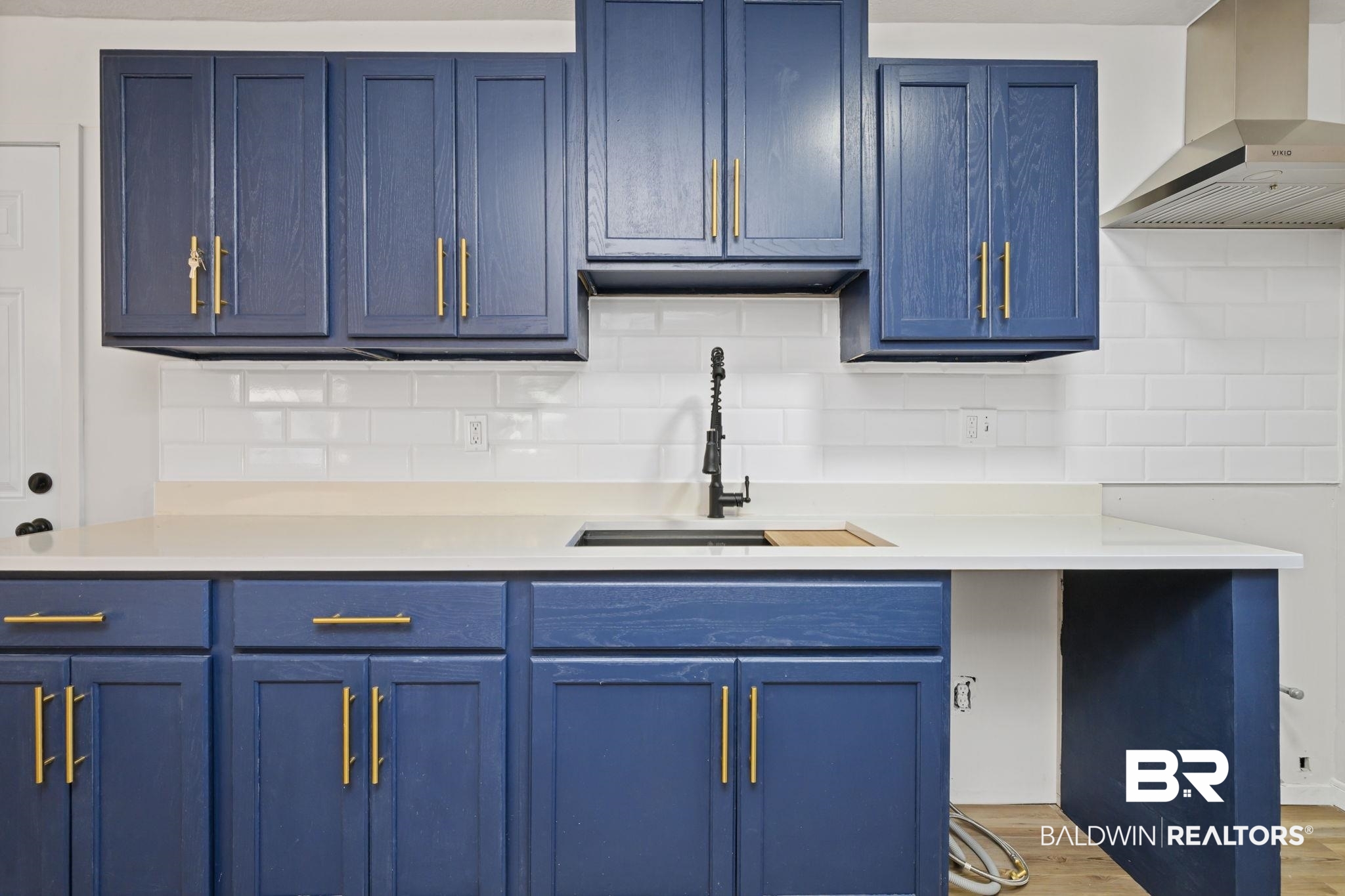 910 Moran Street Bay Minette, AL 36507 - Photo 7 of 20 Kitchen with blue cabinetry, decorative backsplash, and light wood finished floors