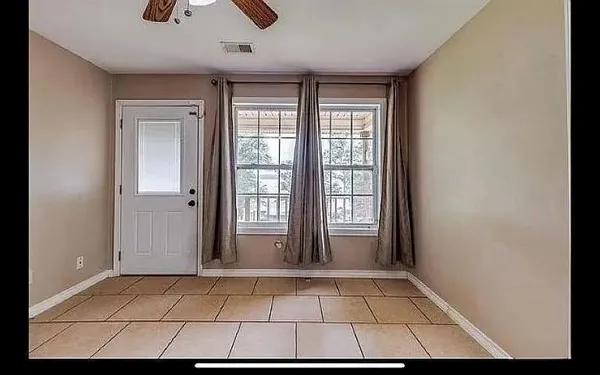 an empty room with a window and a fan