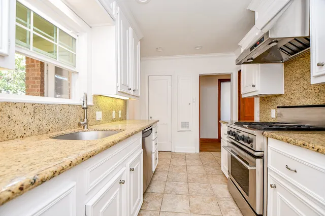 a kitchen with granite countertop a sink stove and cabinets