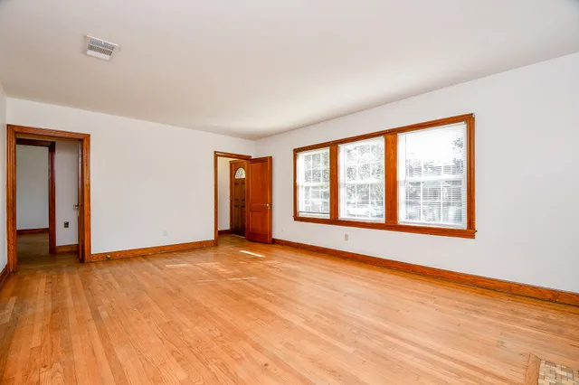 a view of an empty room with wooden floor and a window