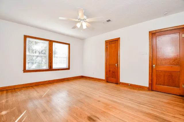 a view of an empty room with window and wooden floor