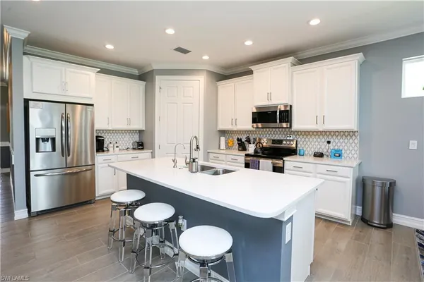 a kitchen with refrigerator a sink and chairs
