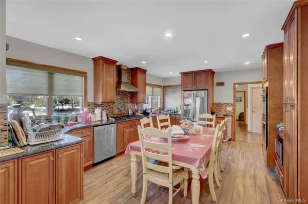 a dining room with stainless steel appliances kitchen island granite countertop a table chairs and a kitchen view